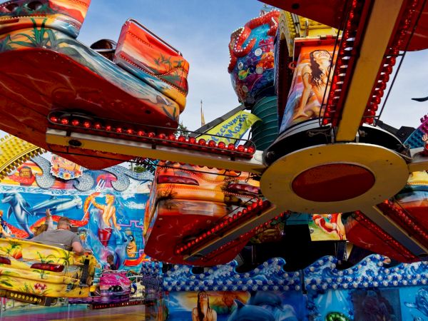 A colorful ocean-themed carnival ride with bright moving boats, LED lights, and painted sea creatures fills the sky with fun.
