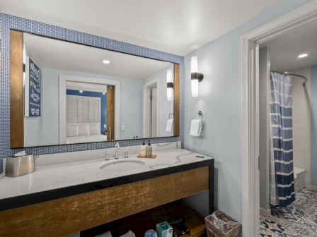 A modern bathroom with a double-sink vanity, large mirror, and striped shower curtain in a tiled room.