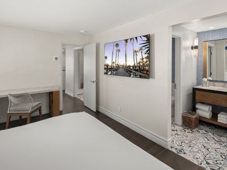 A modern hotel bathroom with double vanity, patterned floor tile, and a palm-bridge wall photo, bright and clean.