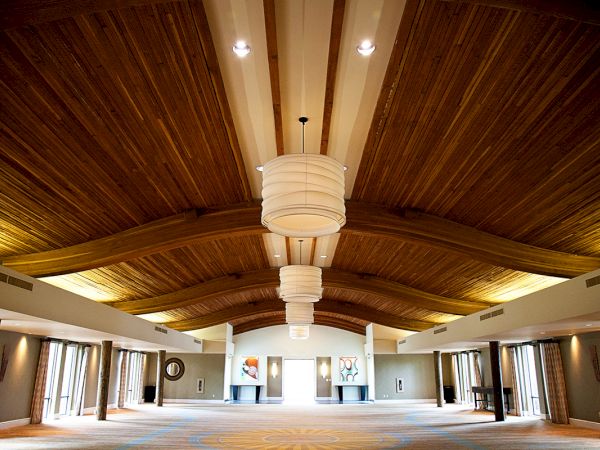 A spacious room with a vaulted wooden ceiling, large globe-like pendant lights, and bright windows.