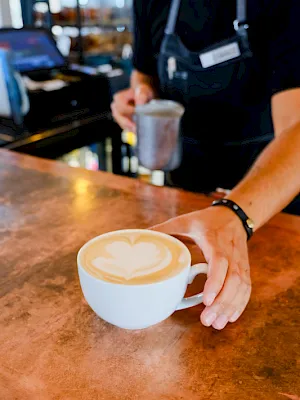 A person holds a small white cup/bowl as another hand reaches toward it in a casual setting.