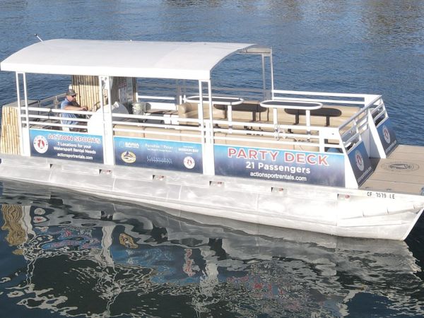 A white pontoon party boat on open water with a &ldquo;PARTY DECK&rdquo; sign for 21 passengers.