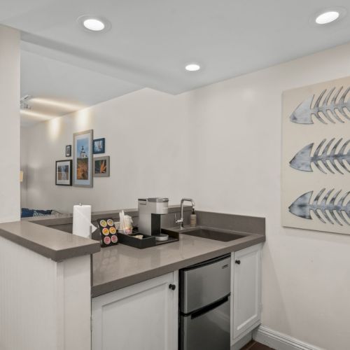A modern kitchen with stainless appliances, a double sink, and fish metal wall art above the counter.