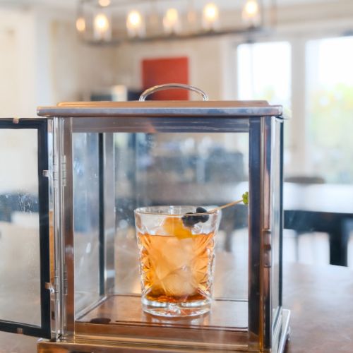 A blurred living room with a wooden-framed glass display showing an orange object in the center.
