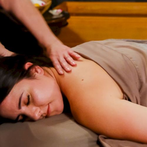 A therapist gives a relaxing massage, pressing hands on a woman&rsquo;s back while she lies on a padded table.