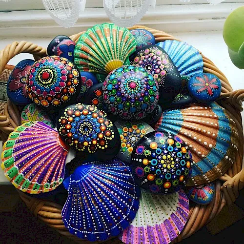 Colorfully painted decorative shells in a wicker basket near a window.