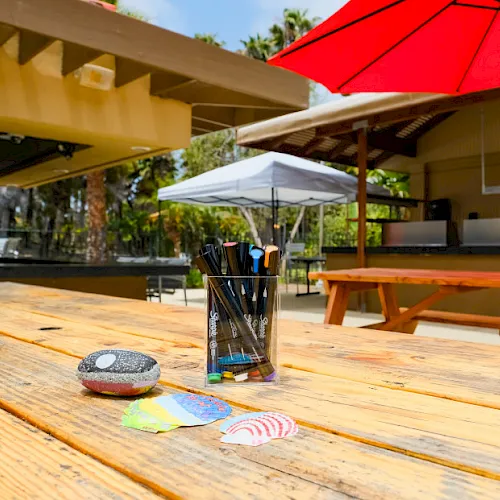 An outdoor courtyard patio with a red umbrella, benches, and a blurred person walking by.