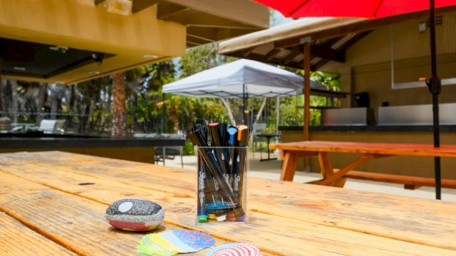 An outdoor courtyard patio with a red umbrella, benches, and a blurred person walking by.