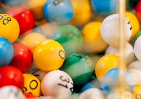 A pile of colorful bouncy balls with smiley faces in a toy bin.