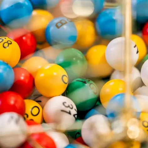 A pile of colorful bouncy balls with smiley faces in a toy bin.