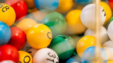 A pile of colorful bouncy balls with smiley faces in a toy bin.