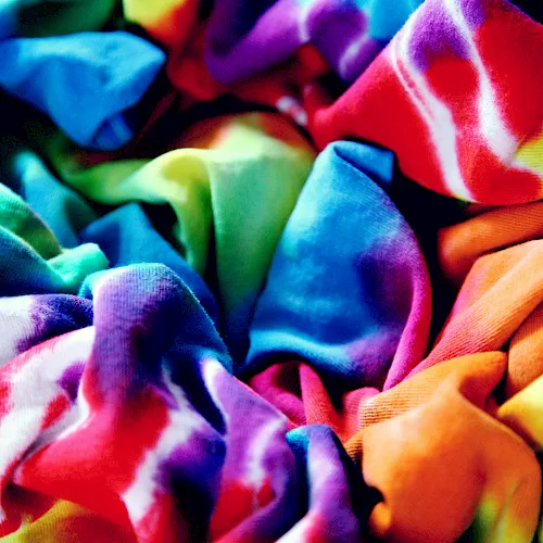 Colorful folded fabrics and clothes fill the frame, with bright reds, blues, greens, and purples.